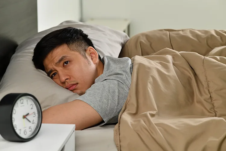 一位民眾因睡眠不足而難以入睡、躺在床上的示意插圖，象徵失眠可能影響全身健康